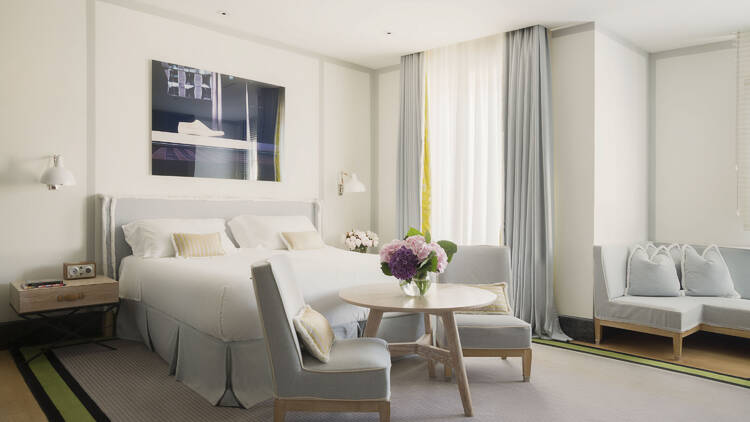 Bedroom at Portrait Roma, with two chairs, a small table and a sofa. Pale blue furnishings