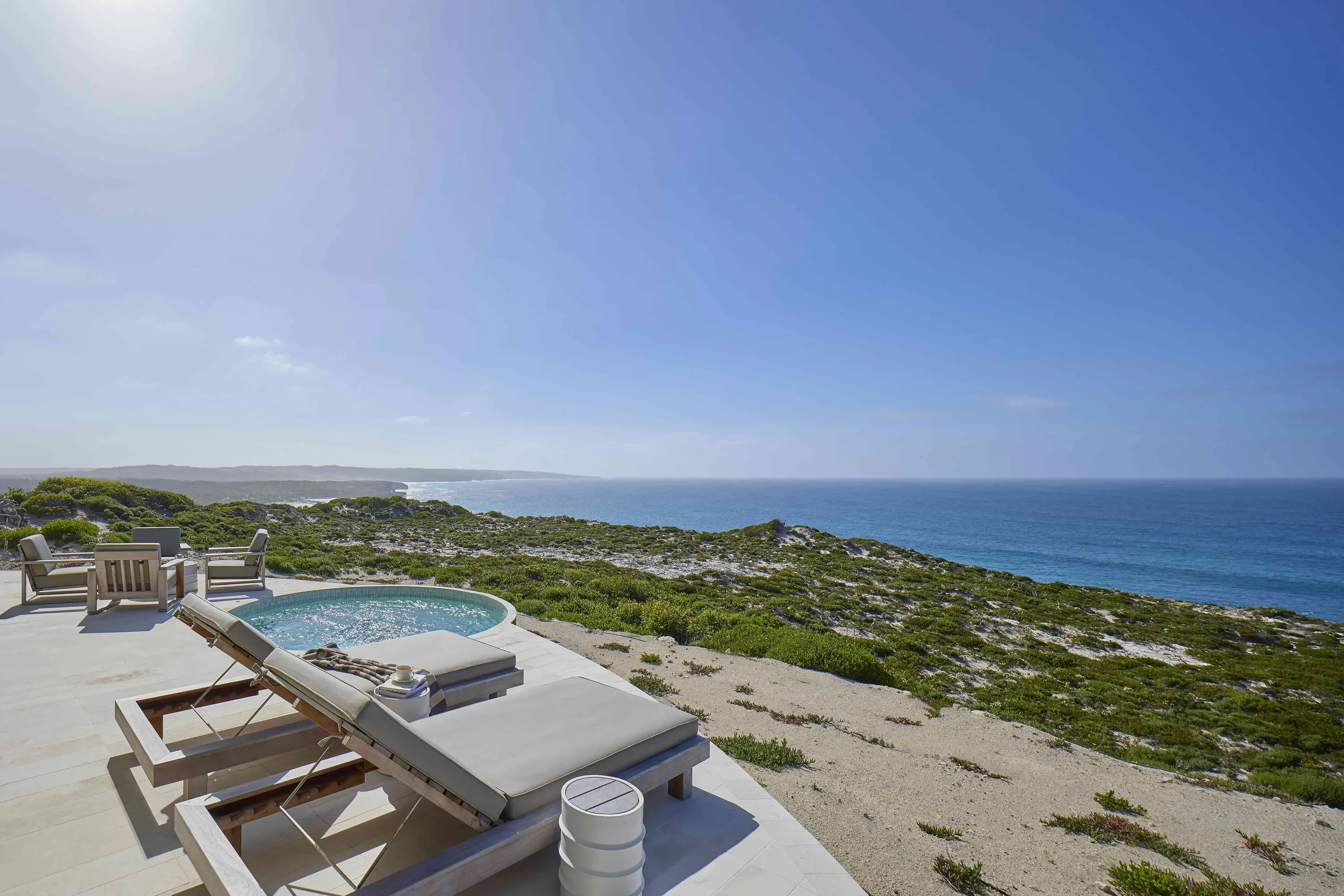 Sun loungers with hot tub on pavilion overlooking ocean