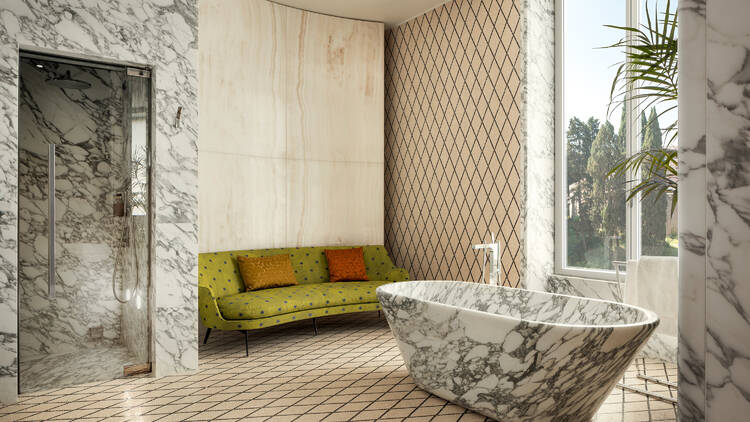 Bathroom in Bulgari Roma suite, with a green sofa and marble walls and bathtub