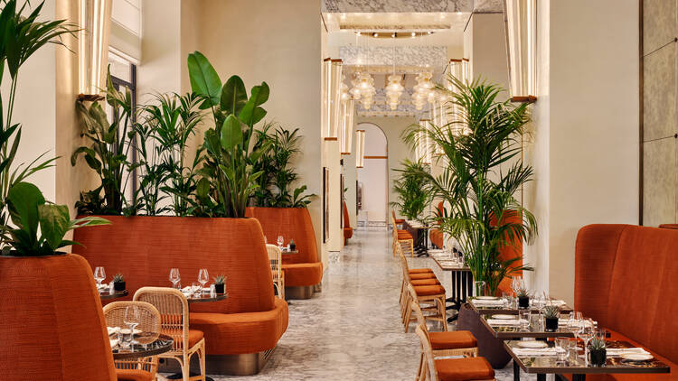 Indoor dining room at Il Caffe in Bulgari Roma, with red sofas and indoor plants
