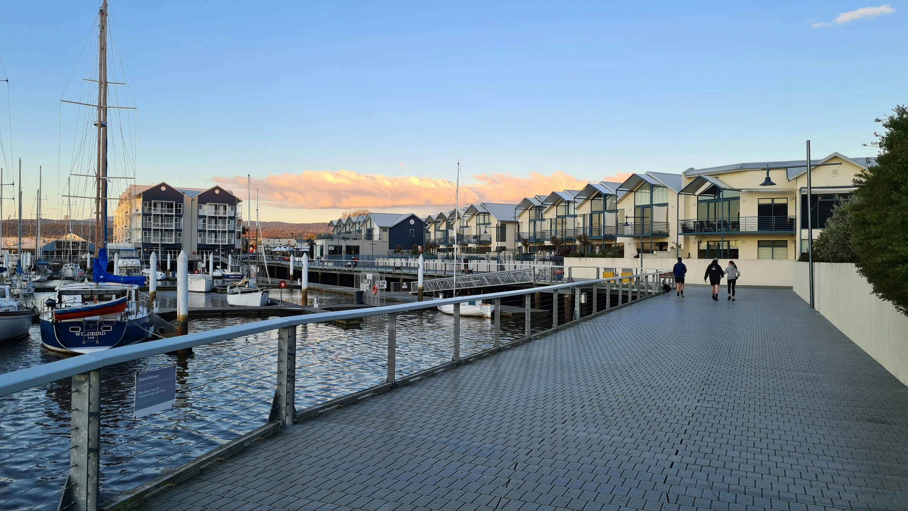 A couple walking down a walkway next to water