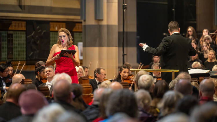 A woman in a red dress singing during Haydn's The Creation by the Royal Melbourne Philharmonic.