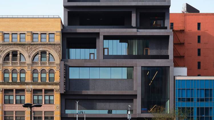 The exterior of the new Studio Museum, a black six-story structure nestled on a busy block.