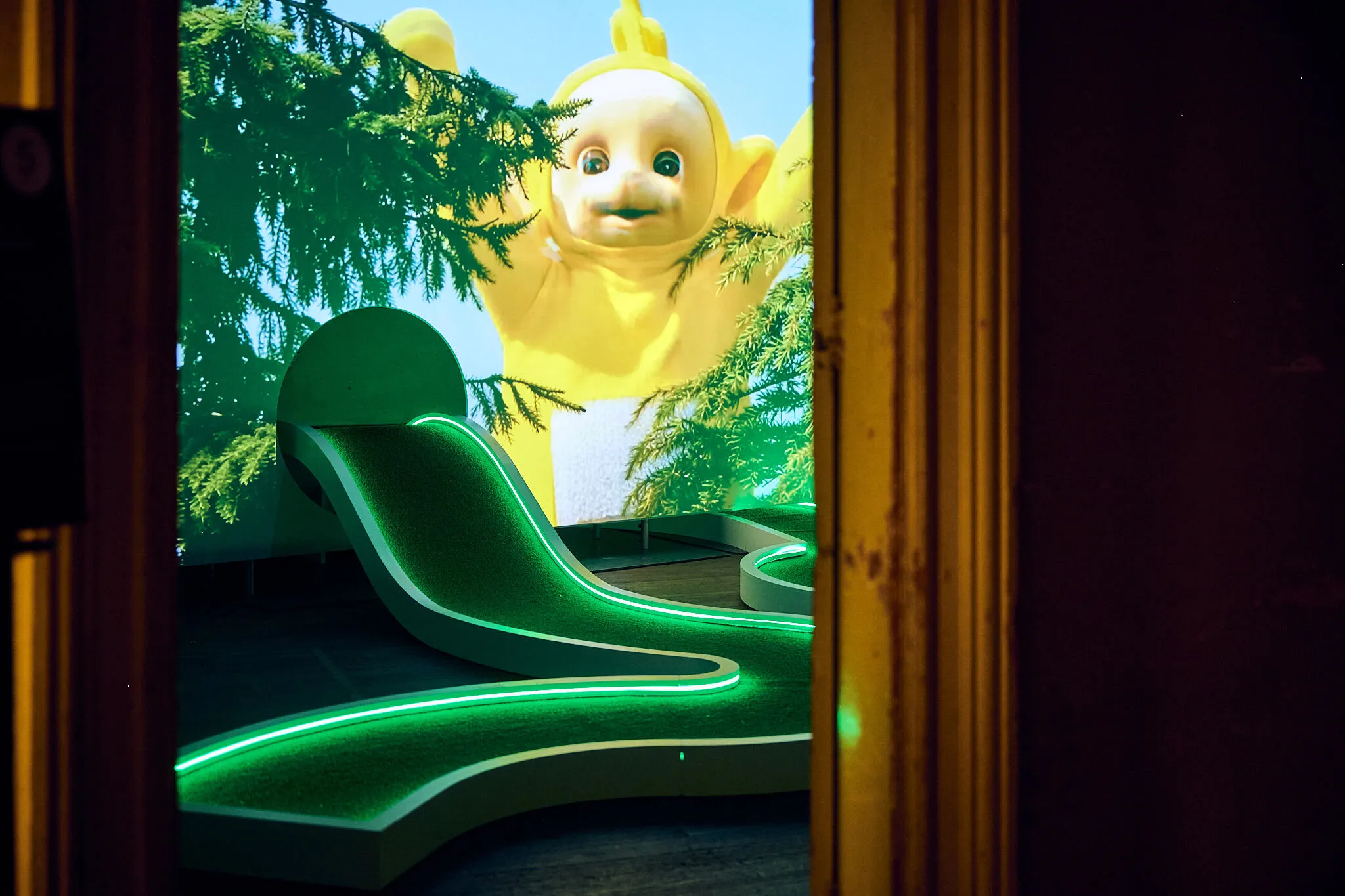 A neon-lit mini golf hole with the yellow Teletubby.