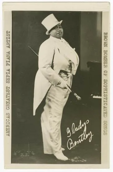 A black-and-white portrait of a person in a top hat and tux holding a cane.