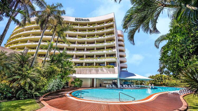 A swimming pool with a hotel in the background. 