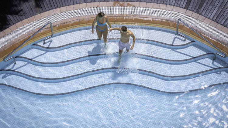 An aerial view of two people walking into a swimming pool