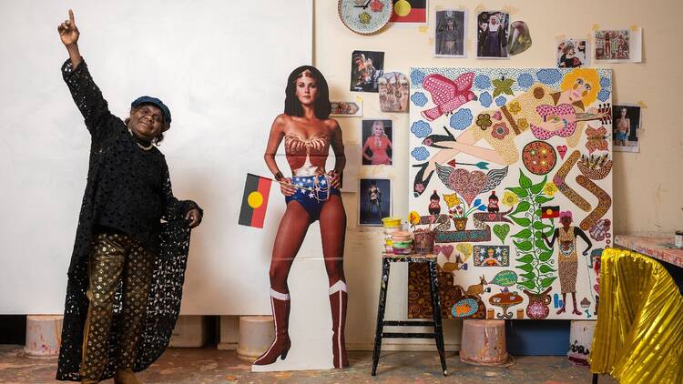 Artist posing next to colourful painting and Wonder Woman stand