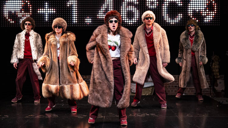 Members of Pony Cam on stage during 'The Orchard' wearing fur coats.