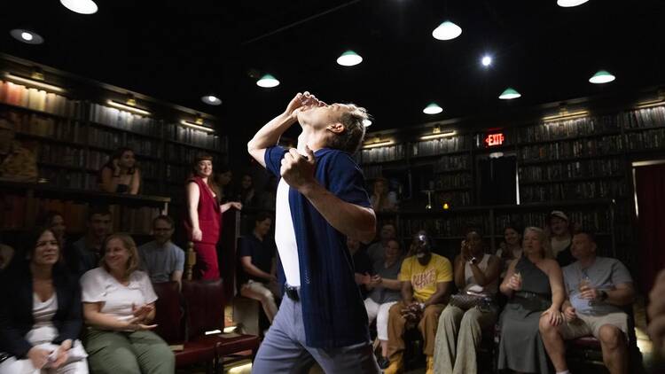 Actor Samuel Adams throws back a shot in the middle of a performance with a delighted audience.