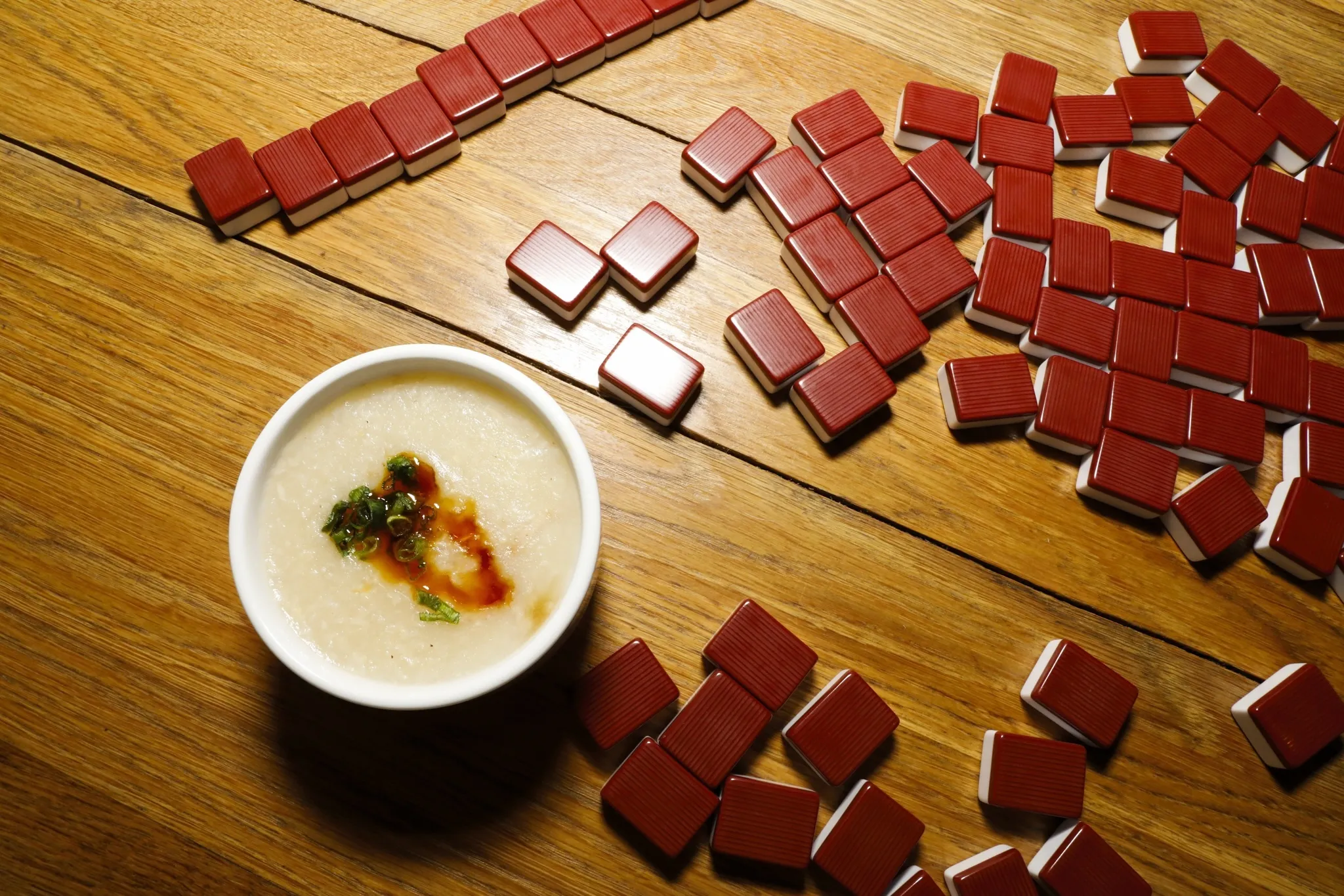 A bowl of jook with red mahjong tiles
