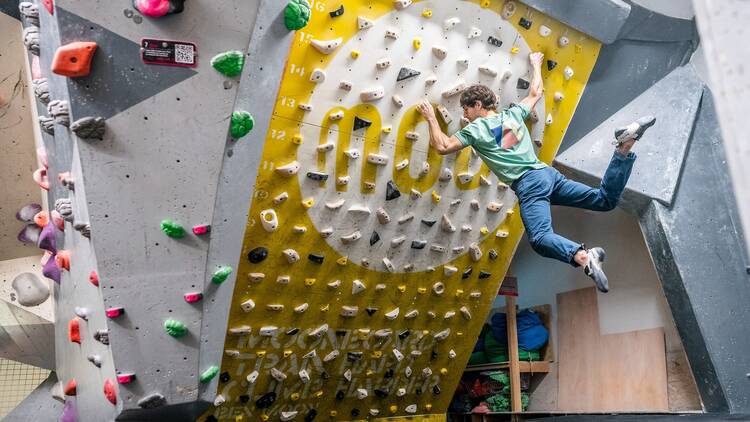 A man hangs off a sloped wall at The Climbing Hangar