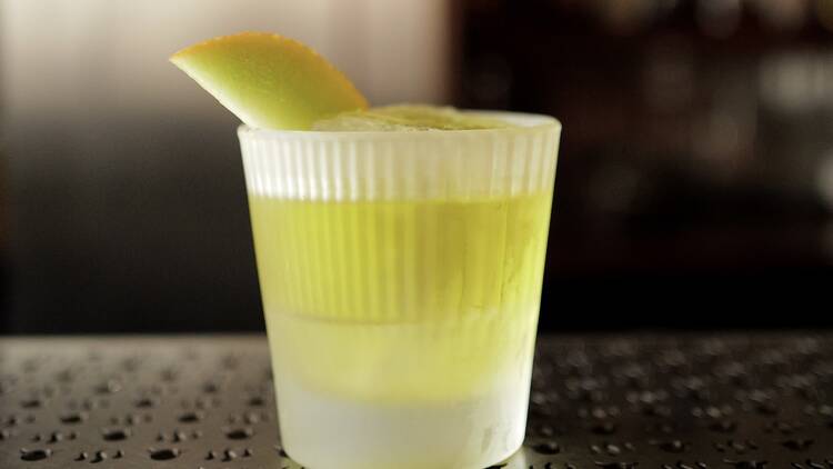 A green cocktail on a metal bar