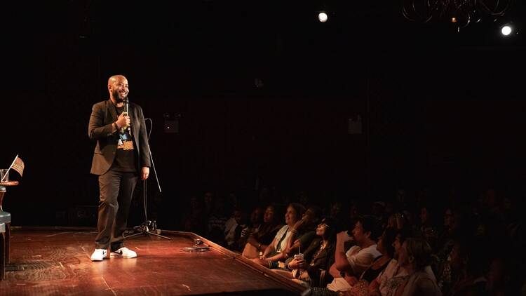 A man standing on stage holding a microphone in front of an audience