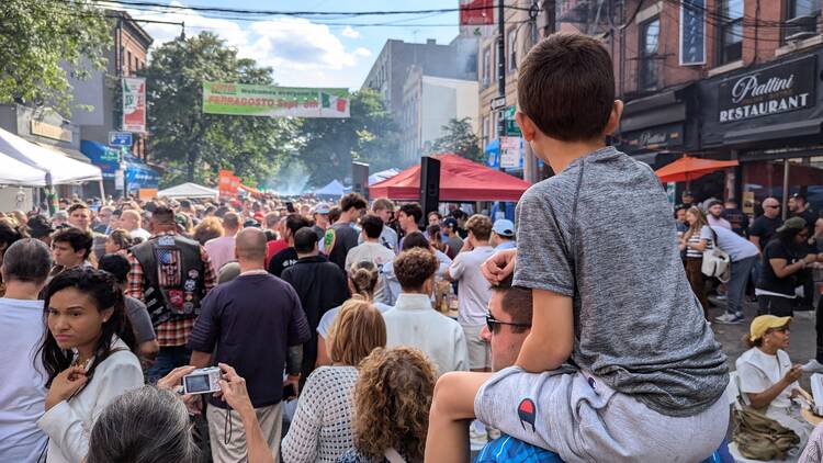 A boy sitting on his dad's shoulders in a crowd of people