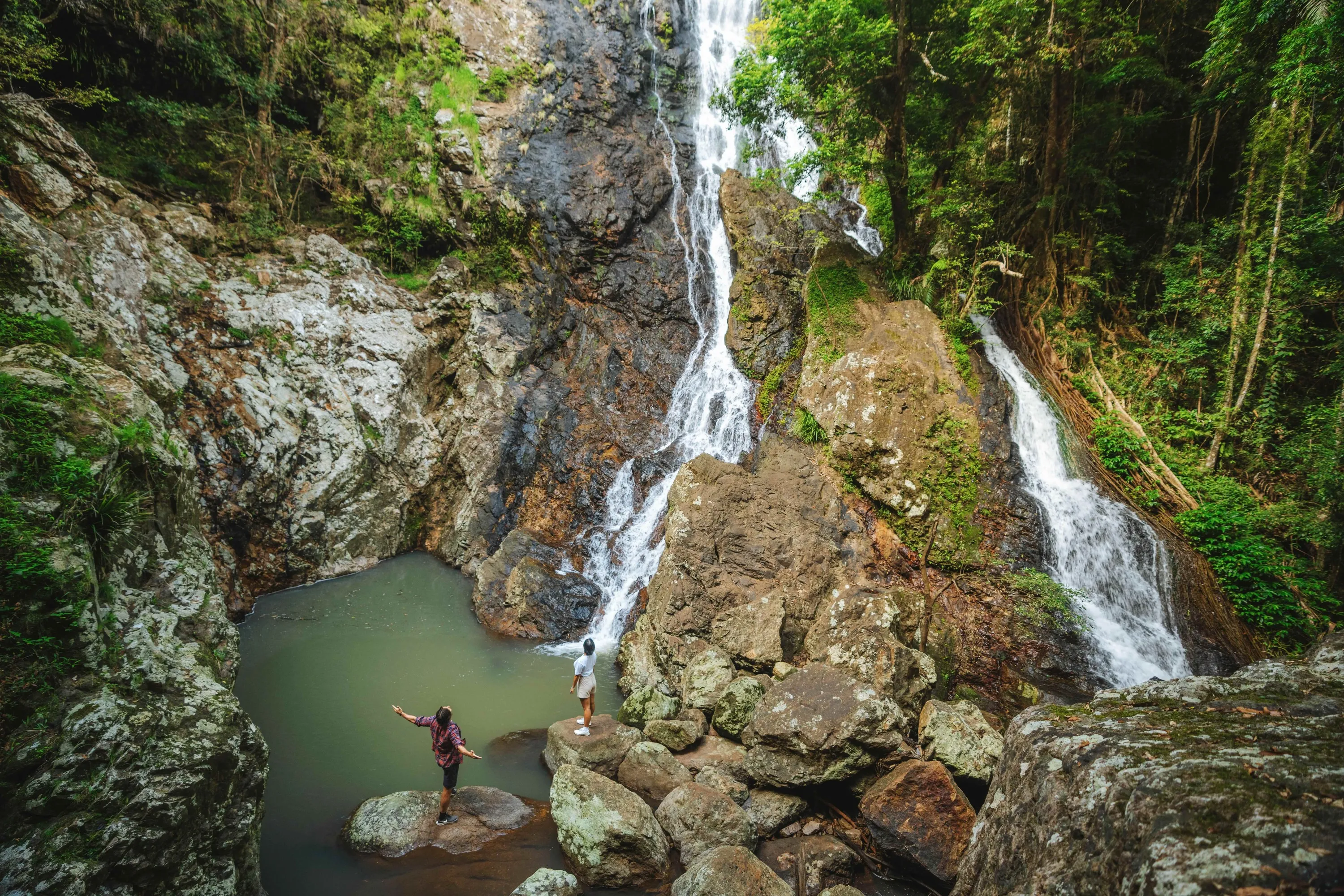 Couple standing on the rocks looking at the rock pool and Kondalilla Falls