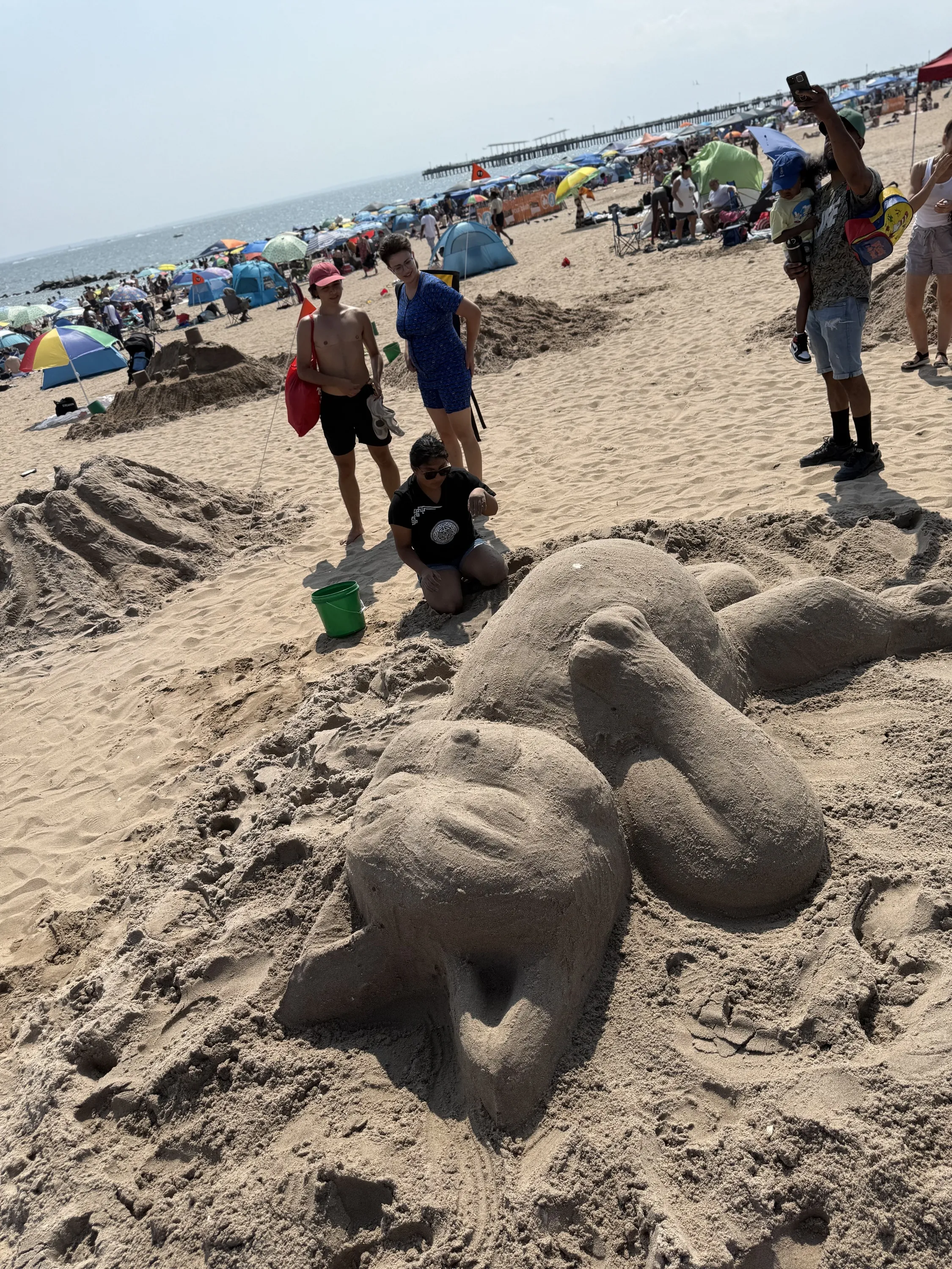 A sand sculpture of a cat with a big belly.