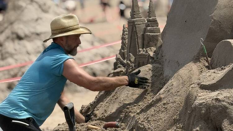 A person works on a sand sculpture.