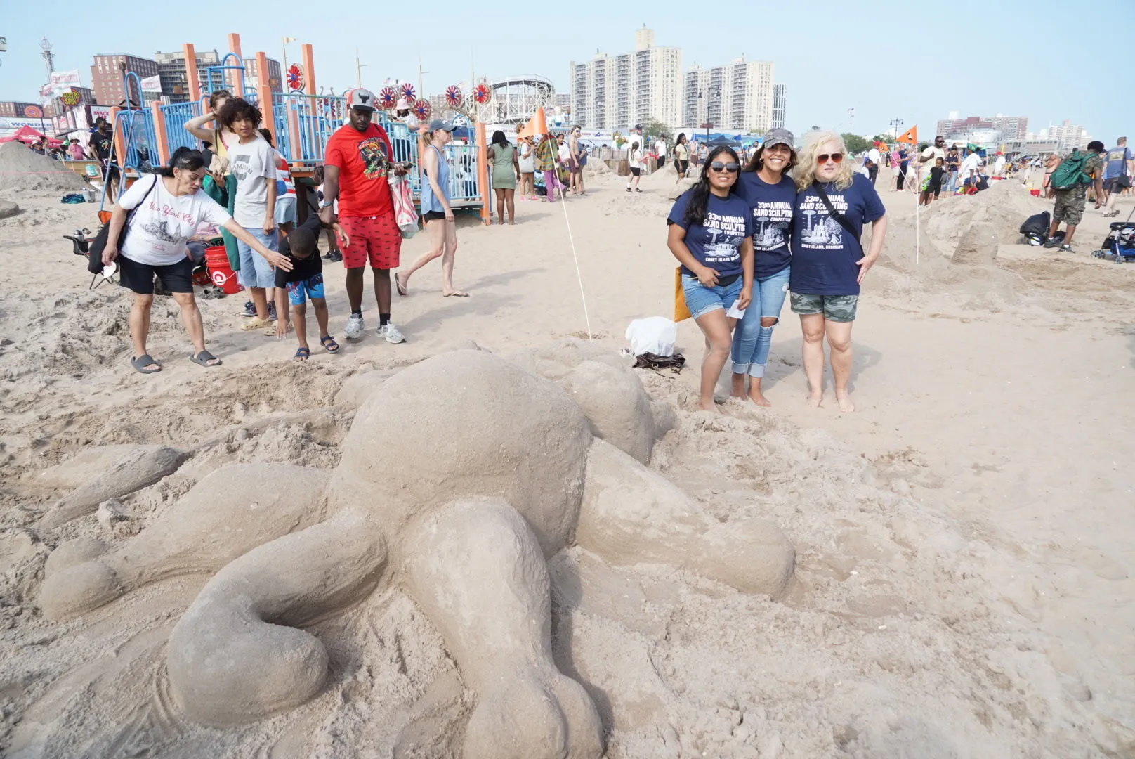 People pose next to a sand sculpture.