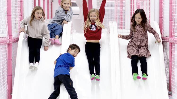 Five kids play on a set of three slides.
