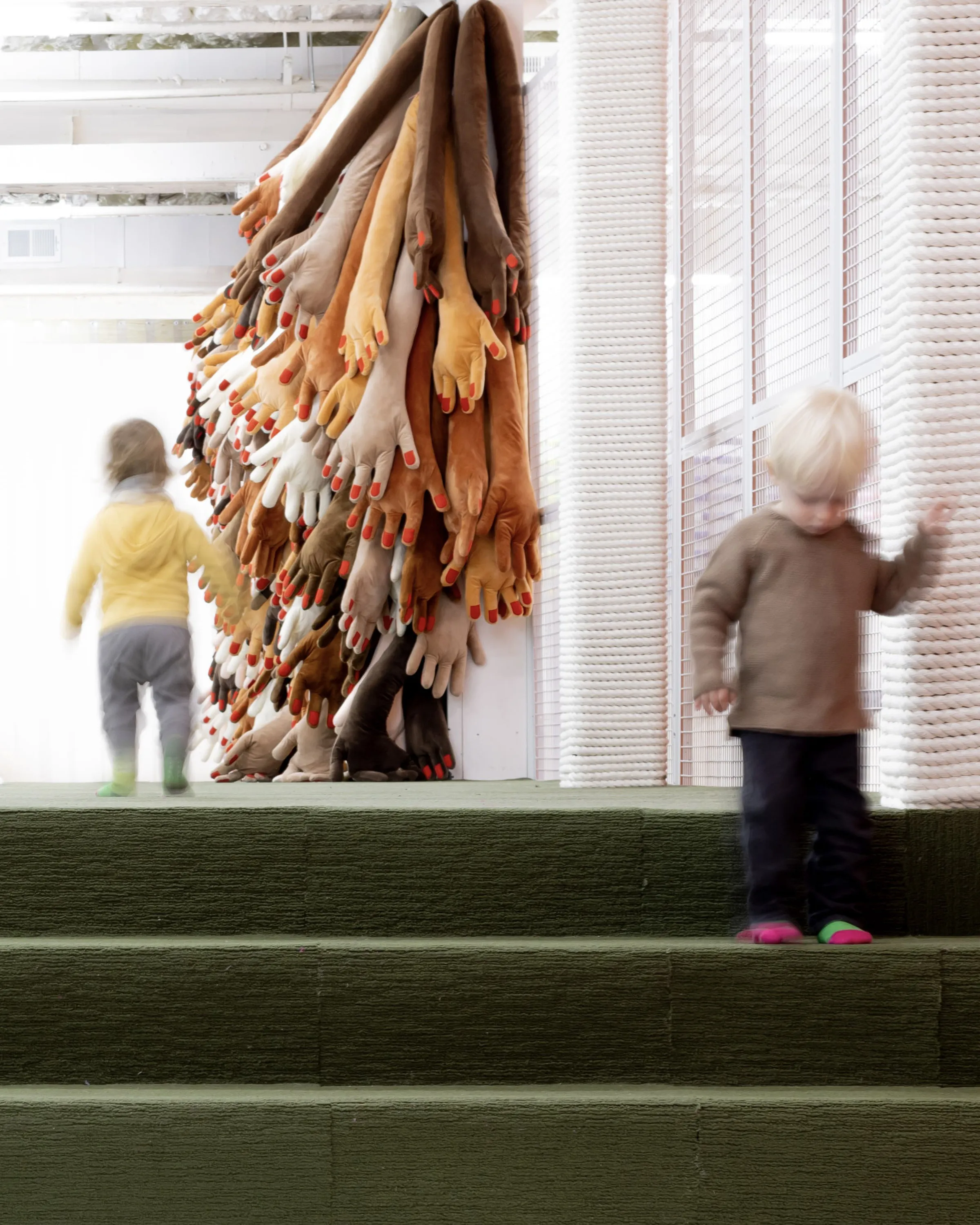 A kid walks in front of a sculpture of hands.