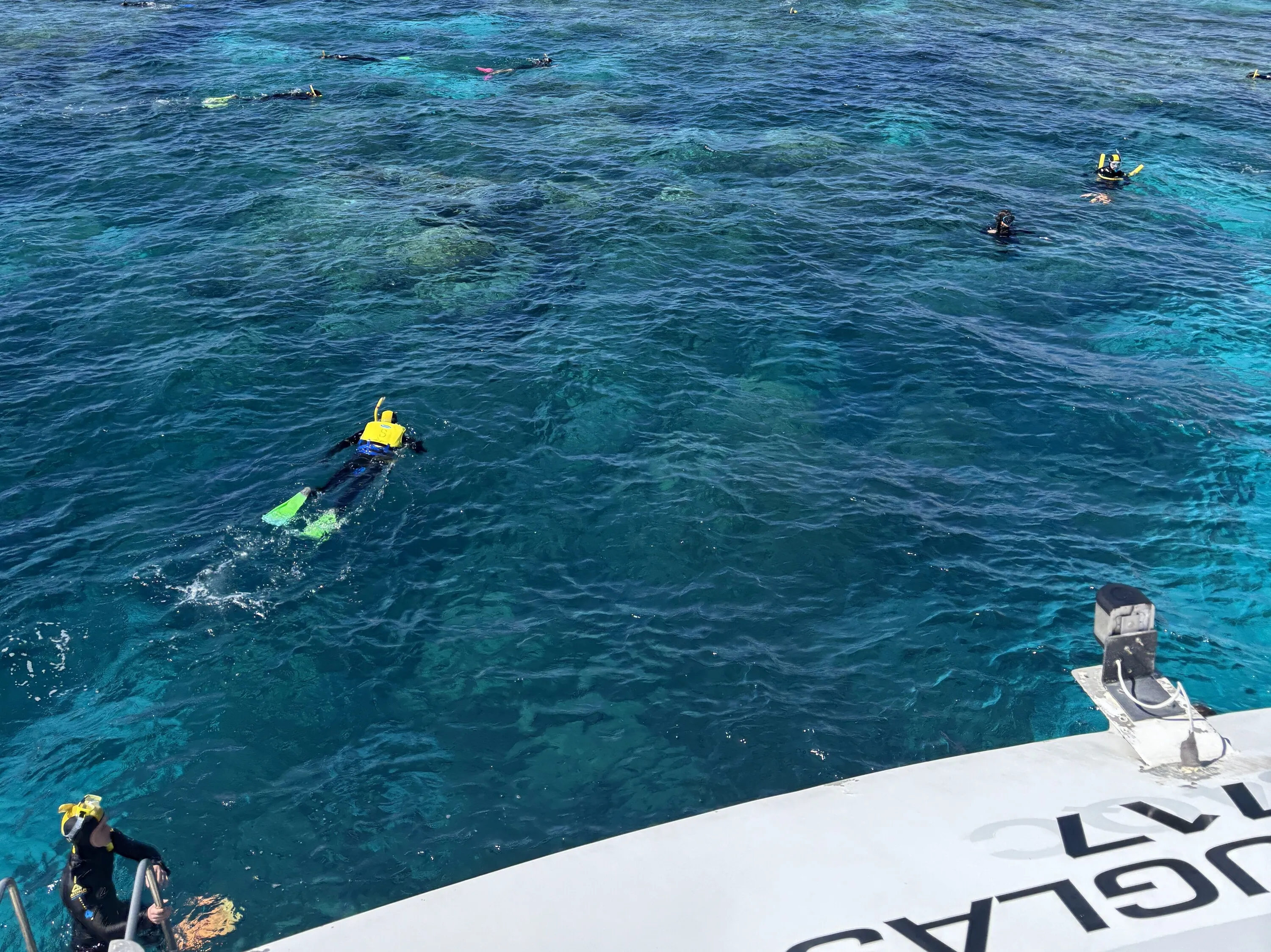 A view of the ocean over a reef, with people snorkelling