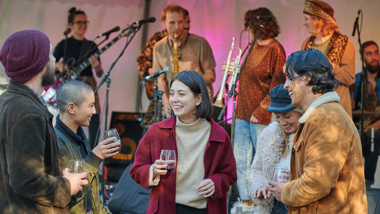 People standing around with a drink listening to music.