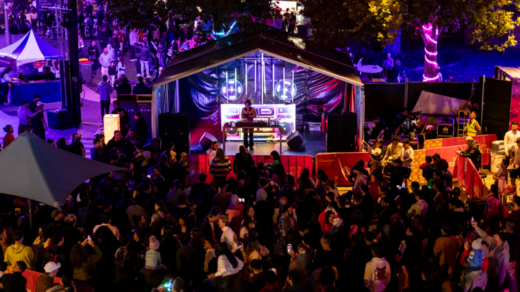 An outdoor music festival stage at night with a big crowd
