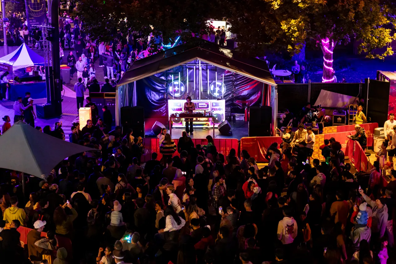 An outdoor music festival stage at night with a big crowd