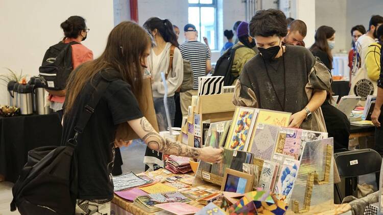 two people looking through a table of books on display
