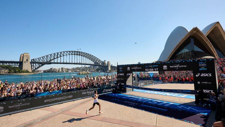 Runner crossing finish line in race at Opera House