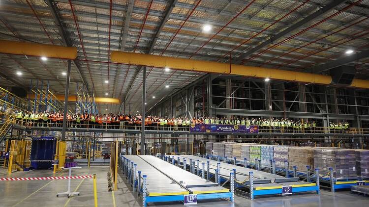A giant warehouse with lots of people on a bridge inside. 