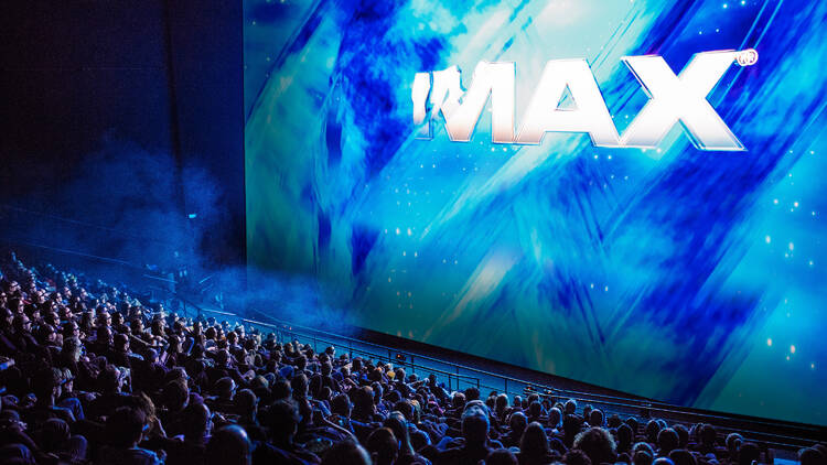 A huge IMAX screen with a crowd of people watching. 