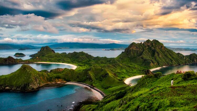 green and brown mountains near body of water under white clouds and blue sky during daytime