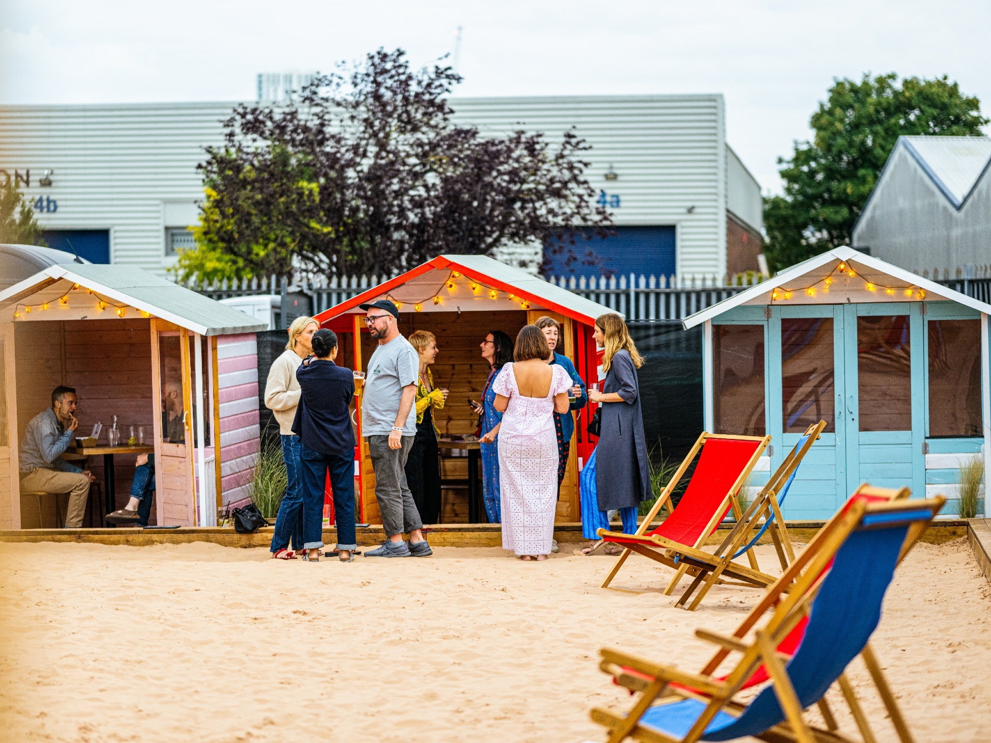 Deckchairs spread out on sand with a line of beach huts in the background at Walthamstow-on-Sea urban beach