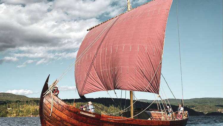 The Saga Farmann, a wooden Viking longboat, sailing on the sea.