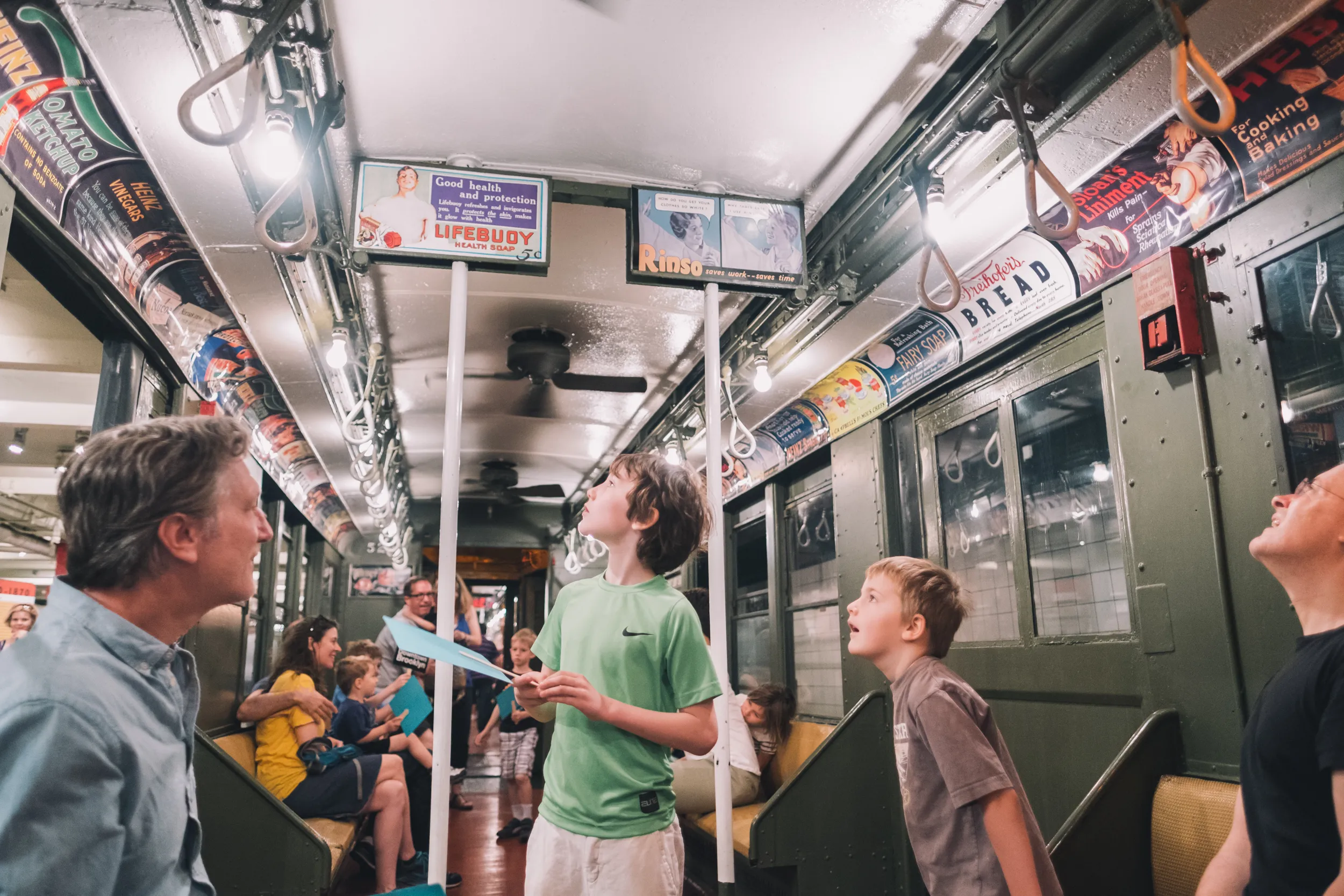 Young boys in a vintage NYC train car reading the advertisements