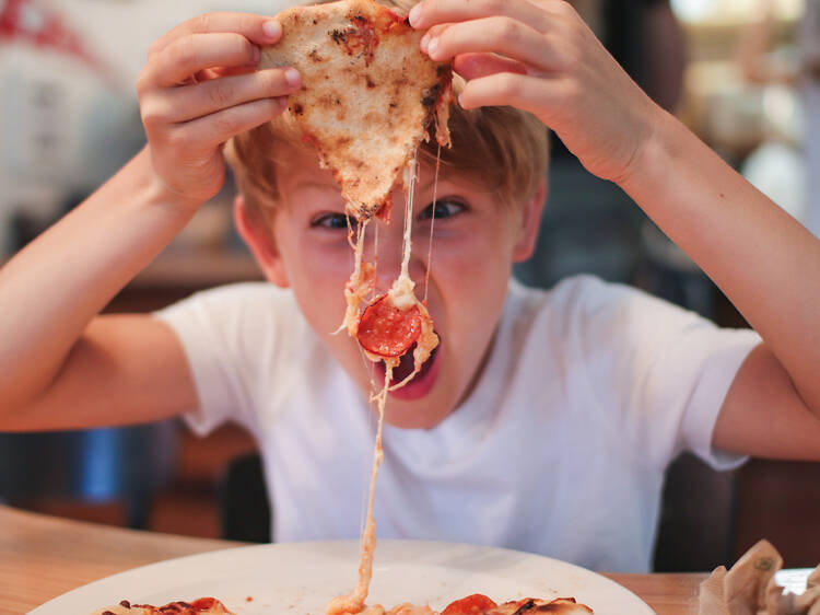 Portrait Of Boy Eating Pepperoni Pizza