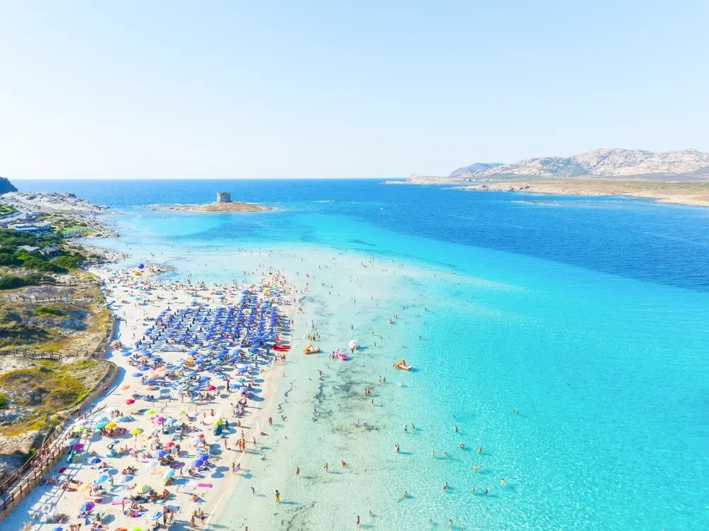 La Pelosa Beach in Sardinia, Italy, with lots of people and parasols