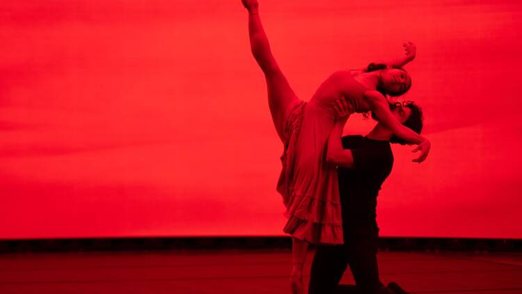 Two ballet dancers hold a pose against a red background. Two ballet dancers hold a pose against a red background.
