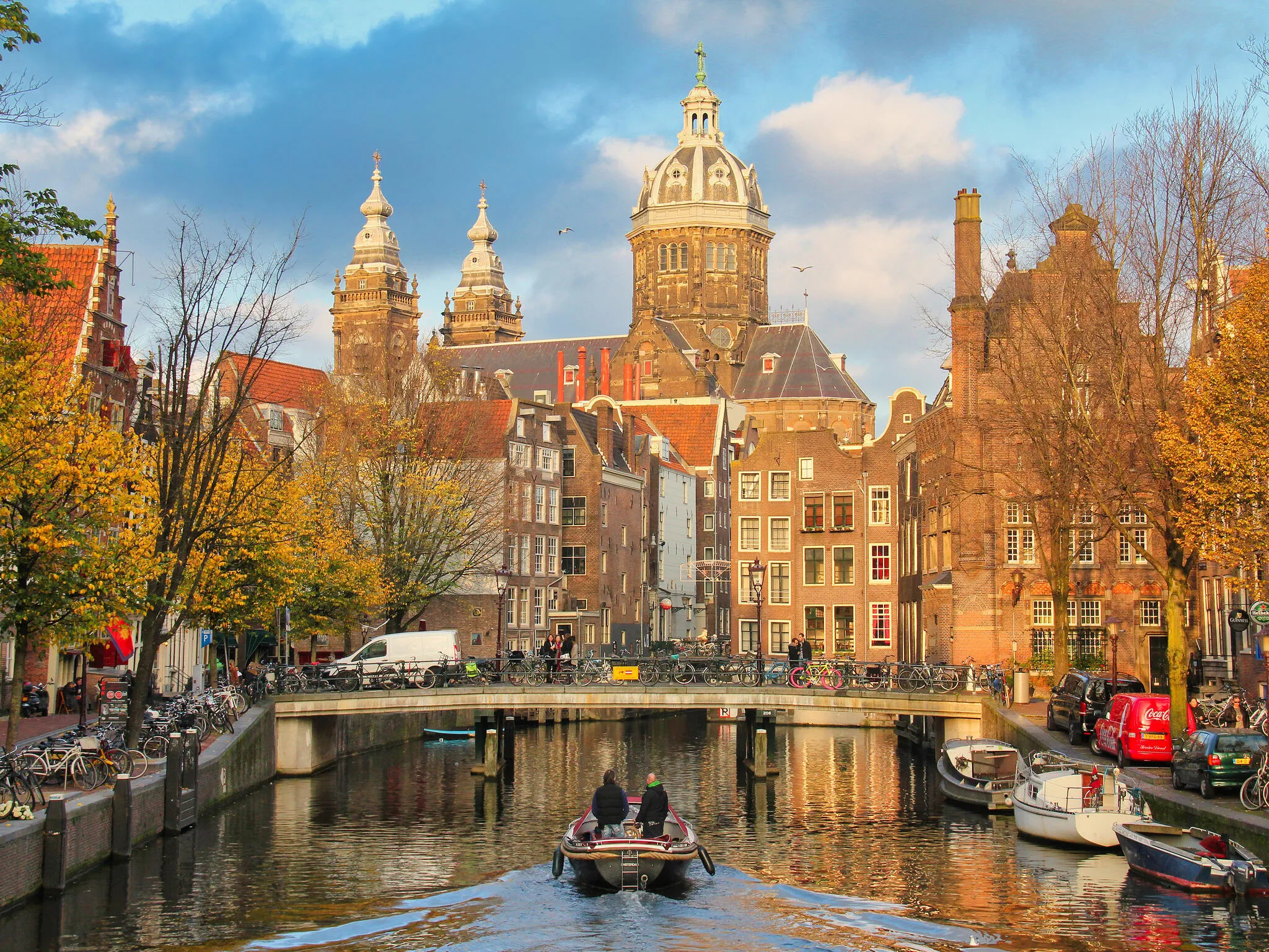 People boating a canal with St. Nicholas church in the background in historical Amsterdam, on November 12, 2015 in Amsterdam, The Netherlands.