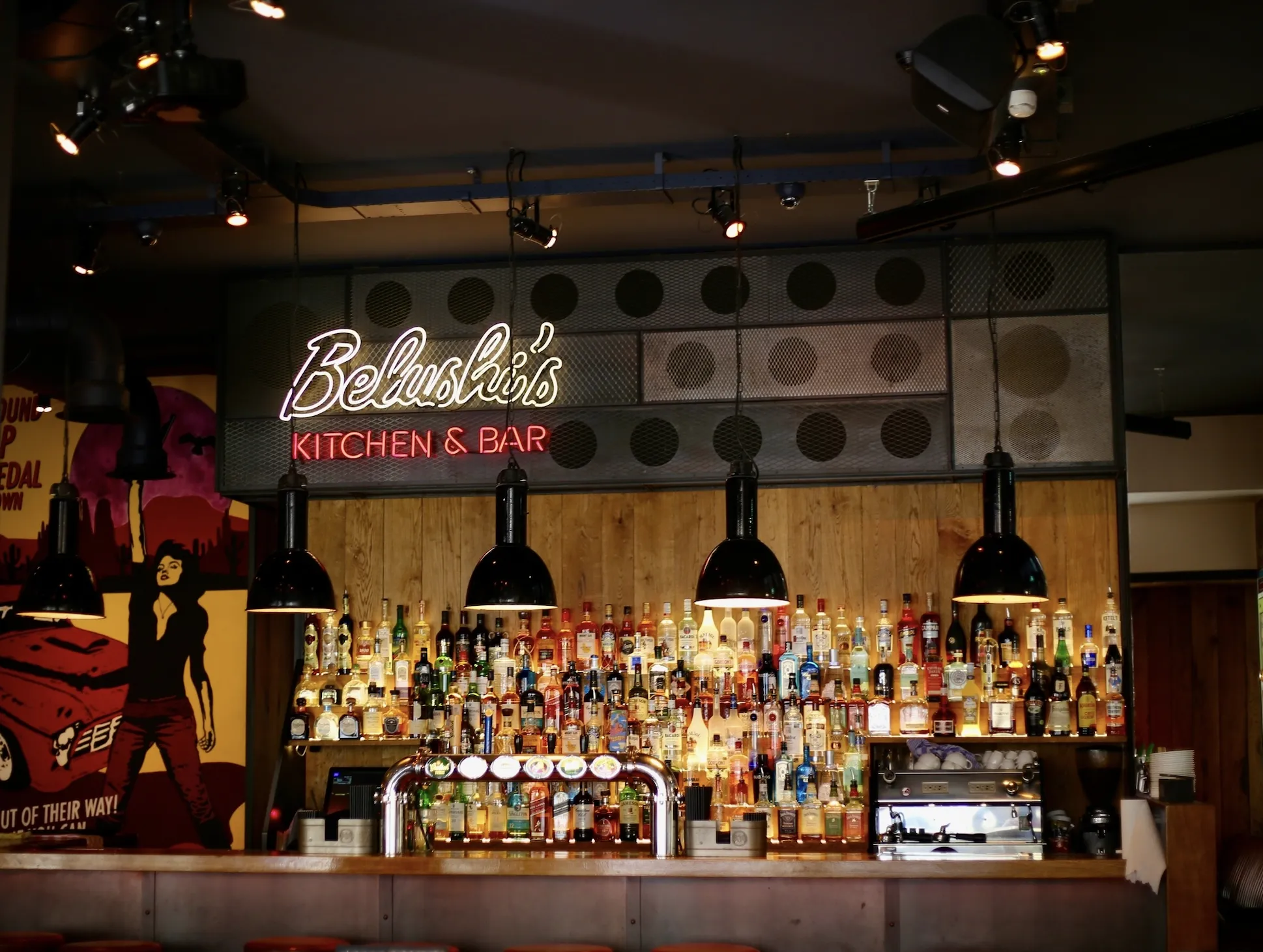 Interior of Belushi’s Bar with colorful bottles and neon sign