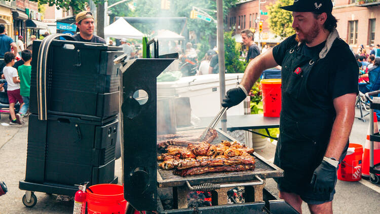A person grilling outdoors in the street