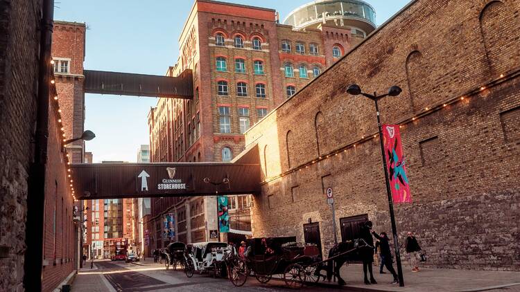 Horse carts waiting for tourists outside Guinness storehouse building. Travel and tourism.