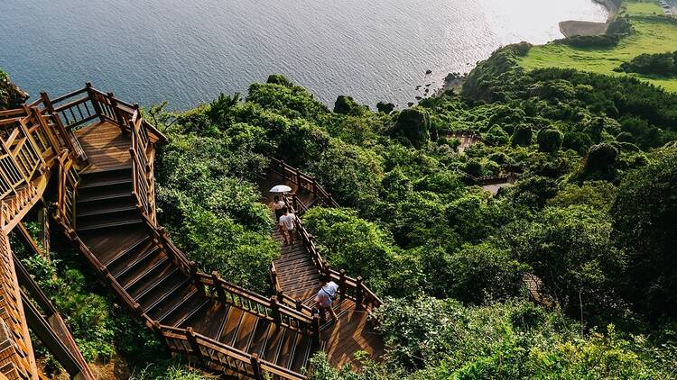 People walking down steps to the sea on Jeju Island in South Korea