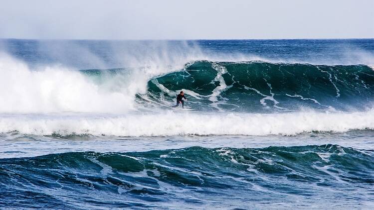 A surfer riding a large wave in Mundaka, Spain