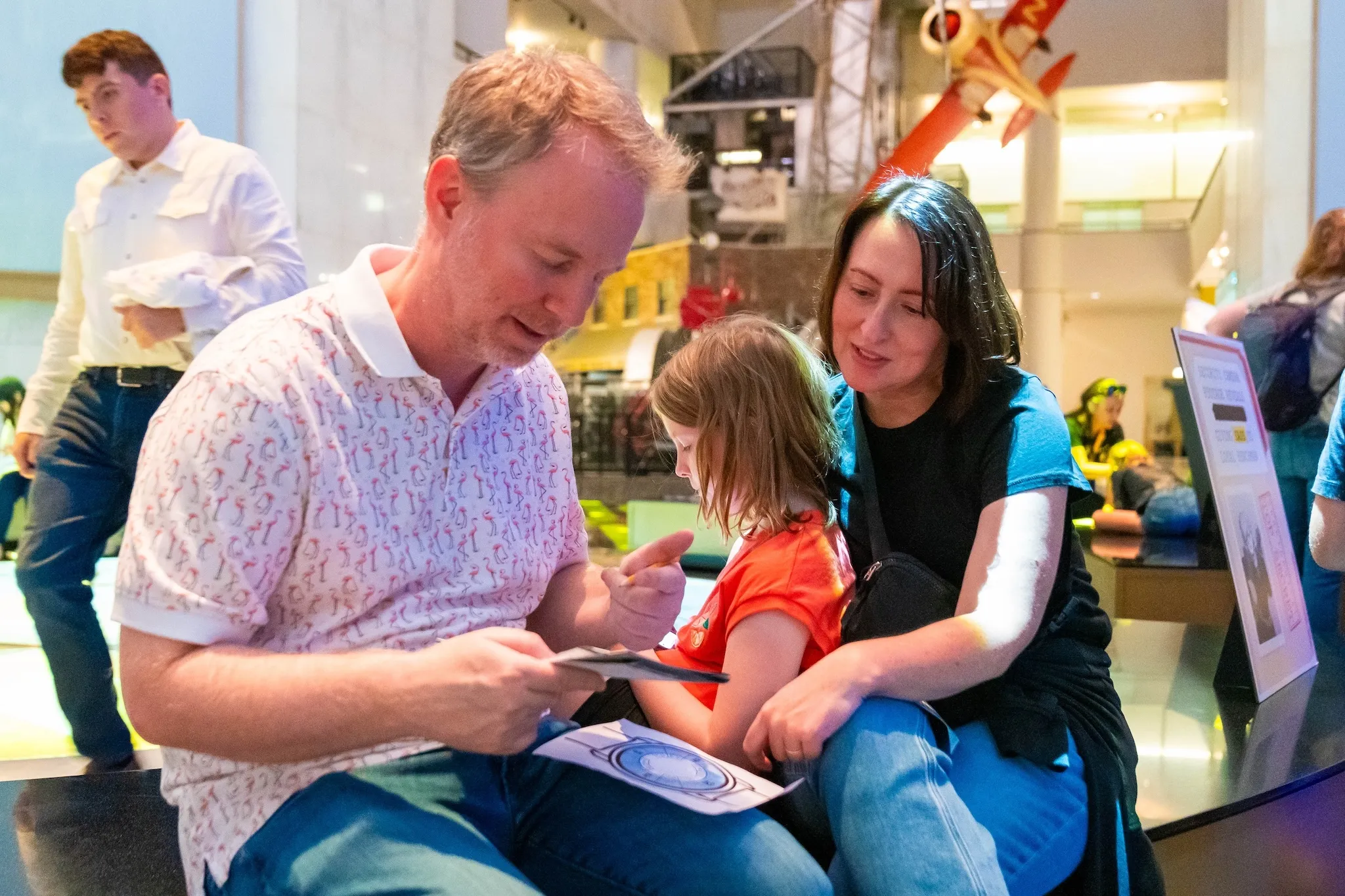 Two parents and a child solve a puzzle together at an "Escape the Museum" event.