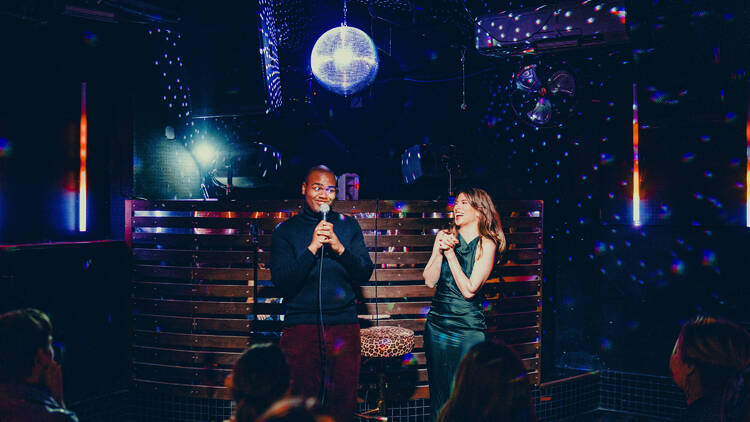 Two performers on stage under a disco ball.