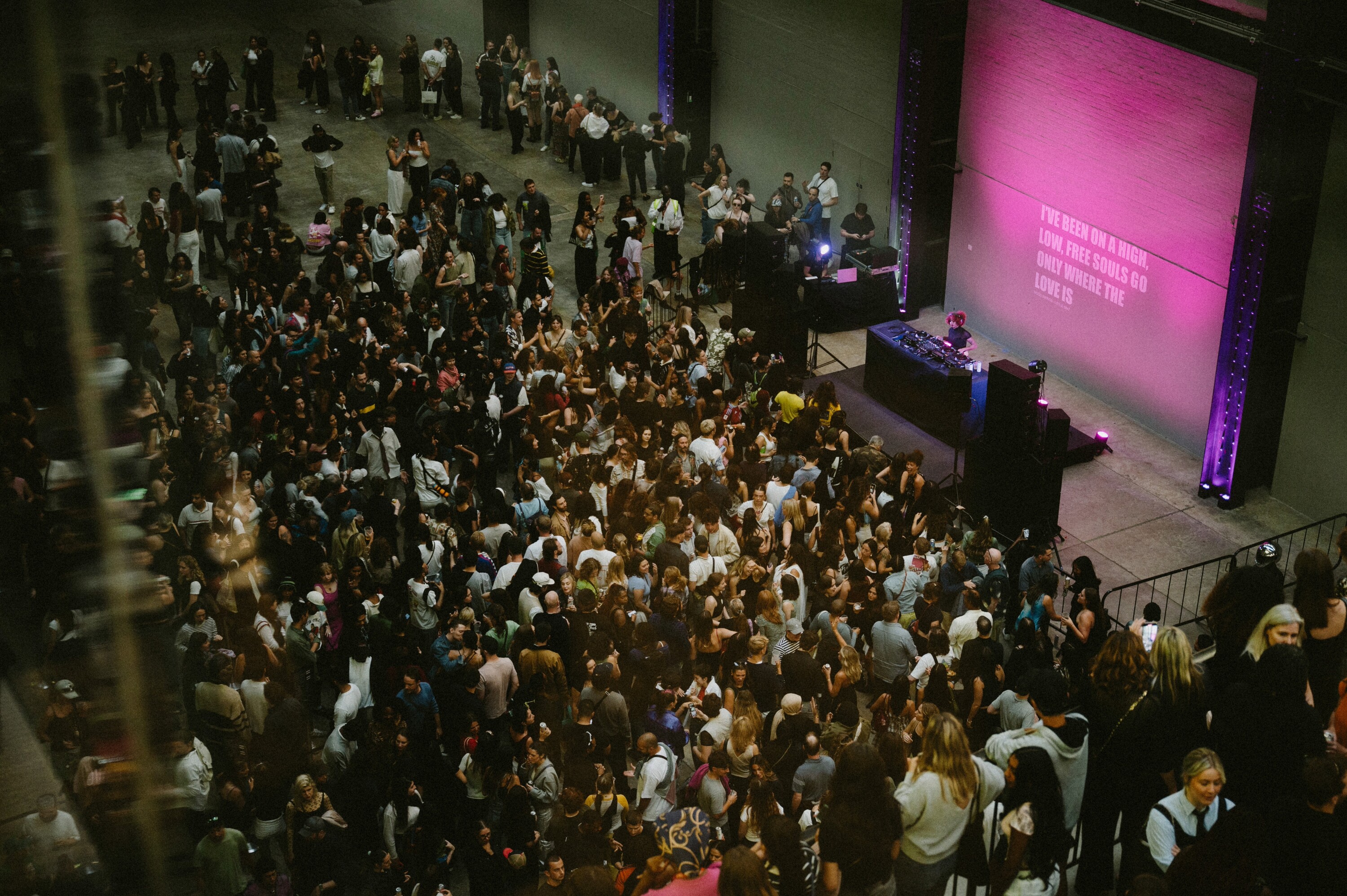 Large crowd gathered in front of a DJ booth inside Tate Modern