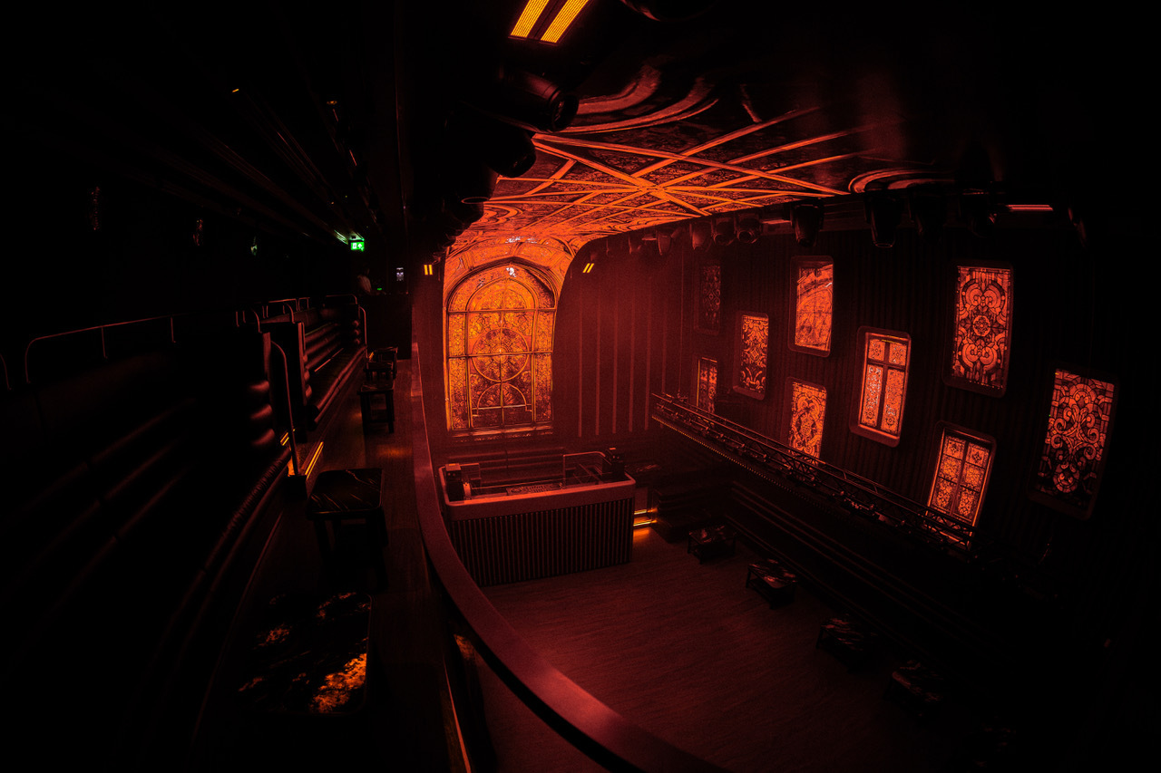 A nightclub with high ceilings and church-like arched windows 